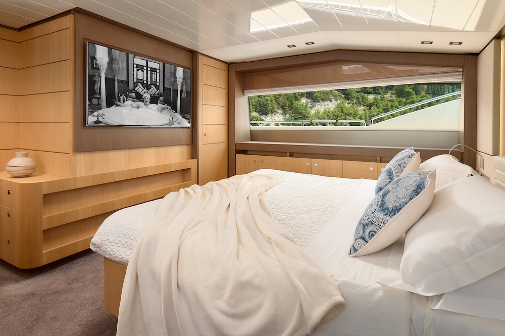Master cabin aboard IVA yacht with natural light and warm wood finishes