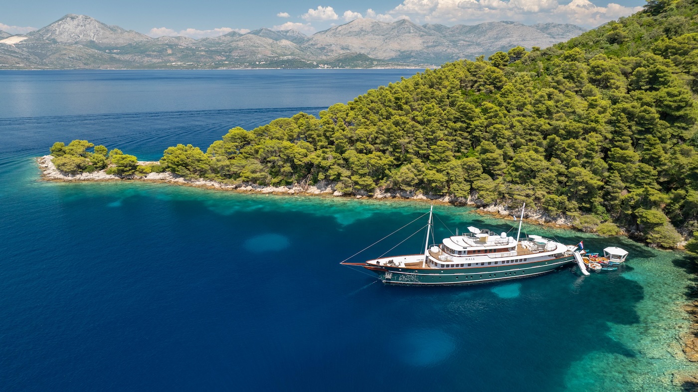 MAIA yacht anchored in a secluded Adriatic bay surrounded by pine forest coastline