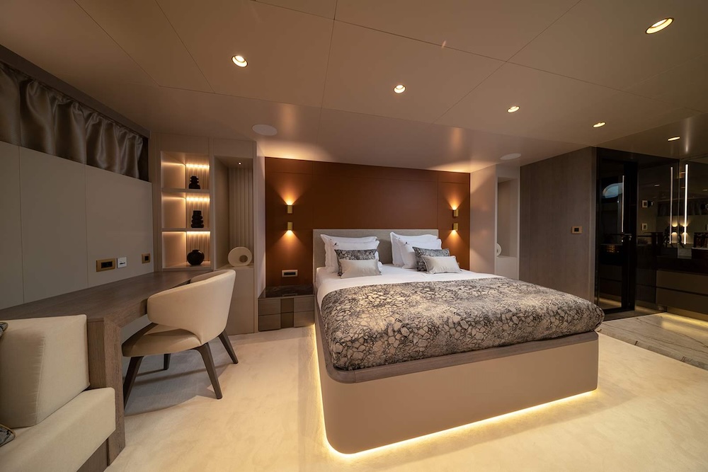 Master cabin aboard S/Y Nocturno with warm lighting, soft textures, and integrated lounge space