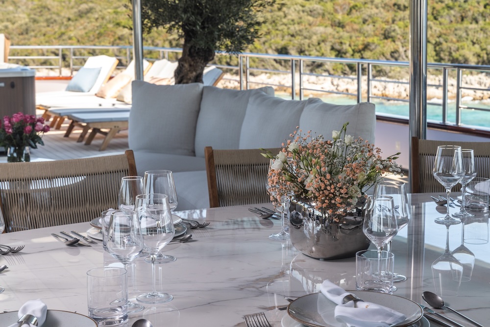 Elegant outdoor dining table setup on Olimp yacht with refined table styling and sea views
