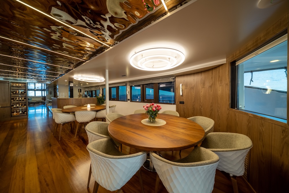 Indoor dining area on Olimp yacht with warm wood finishes and a relaxed coastal atmosphere