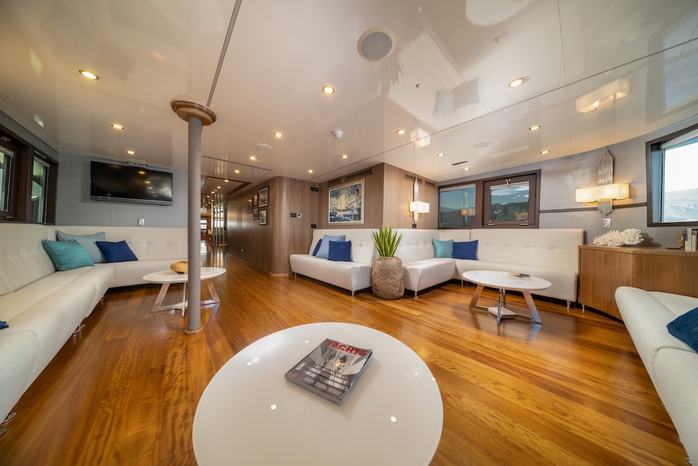 Main salon on Olimp yacht with open lounge seating and warm wood finishes