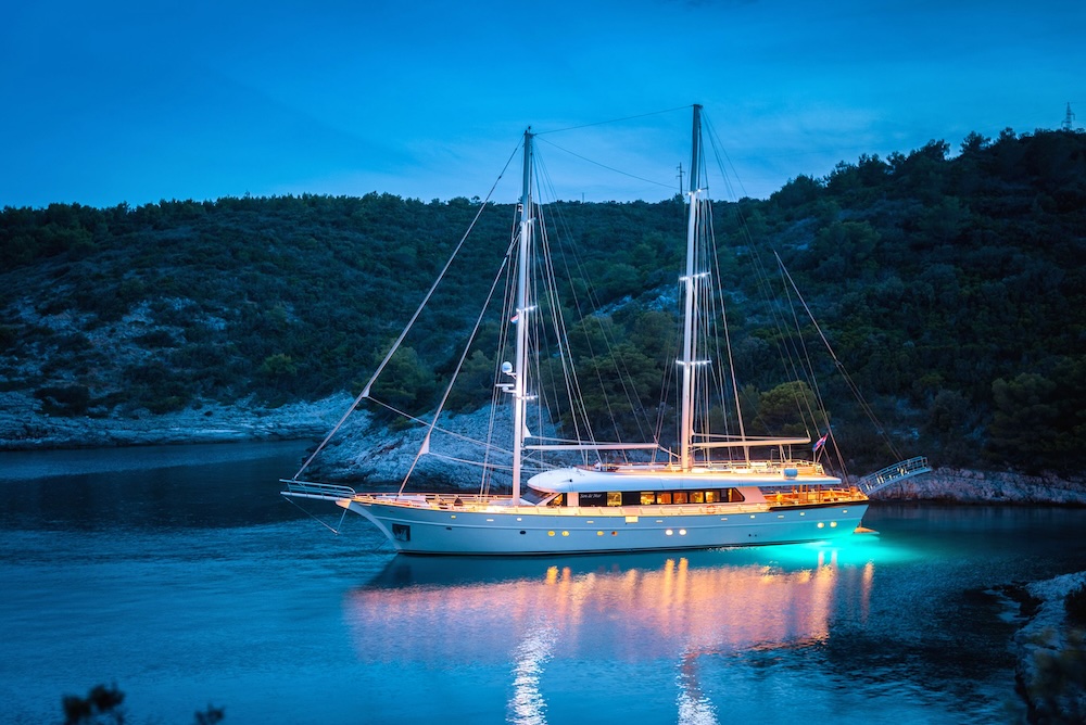 Son de Mar illuminated at anchor during a calm evening in a secluded bay