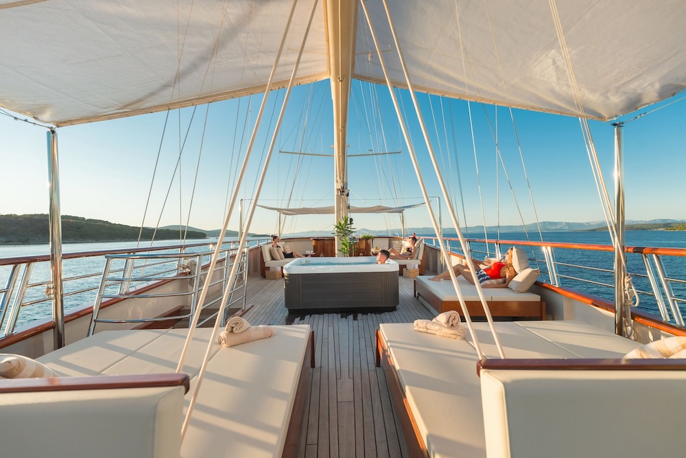 Guests relaxing on upper deck of Son de Mar with coastal views