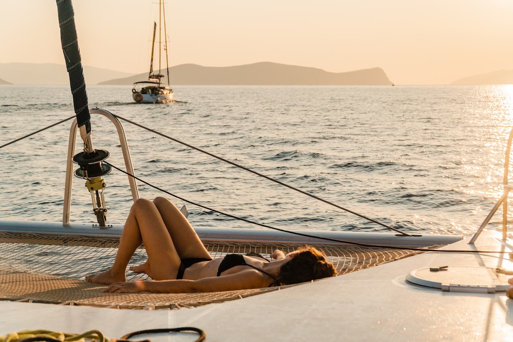Guest relaxing on the deck of a sailing yacht at golden hour, surrounded by calm sea and an unhurried atmosphere