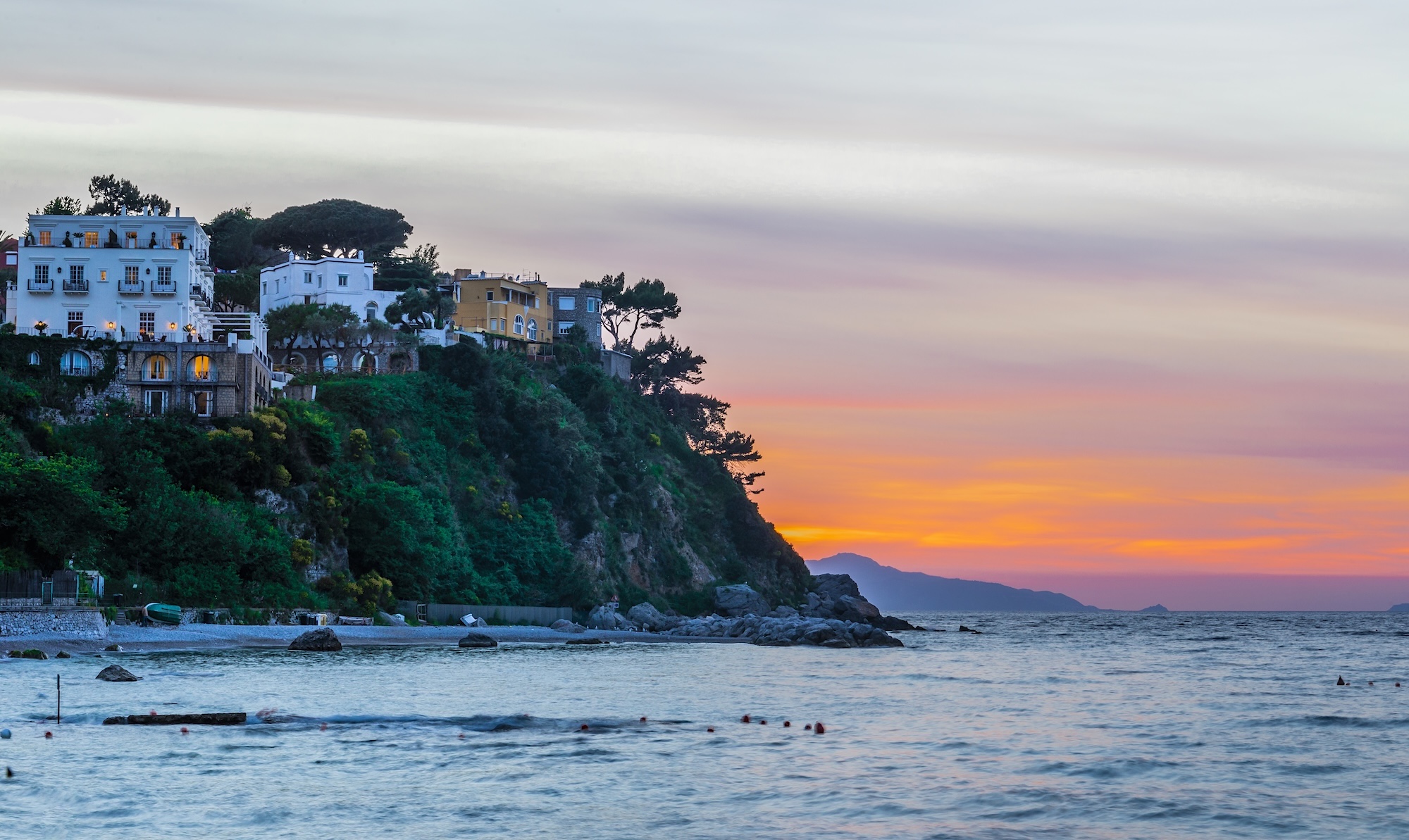 Amalfi Coast coastal village at sunset with calm Mediterranean sea and soft pastel sky in Italy