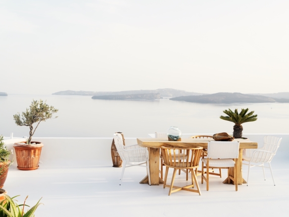 Coastal terrace with dining table overlooking calm sea in soft natural light