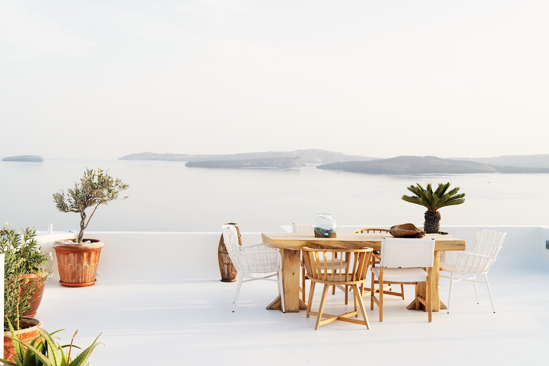Coastal terrace with dining table overlooking calm sea in soft natural light