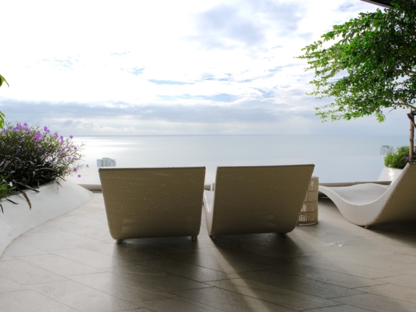 Coastal terrace with lounge chairs overlooking calm sea in natural light
