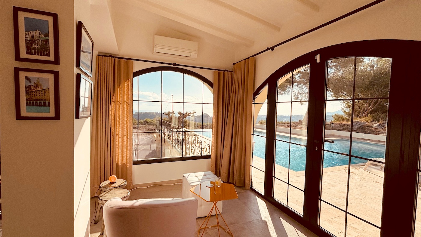 Bright villa interior with large windows opening to pool terrace