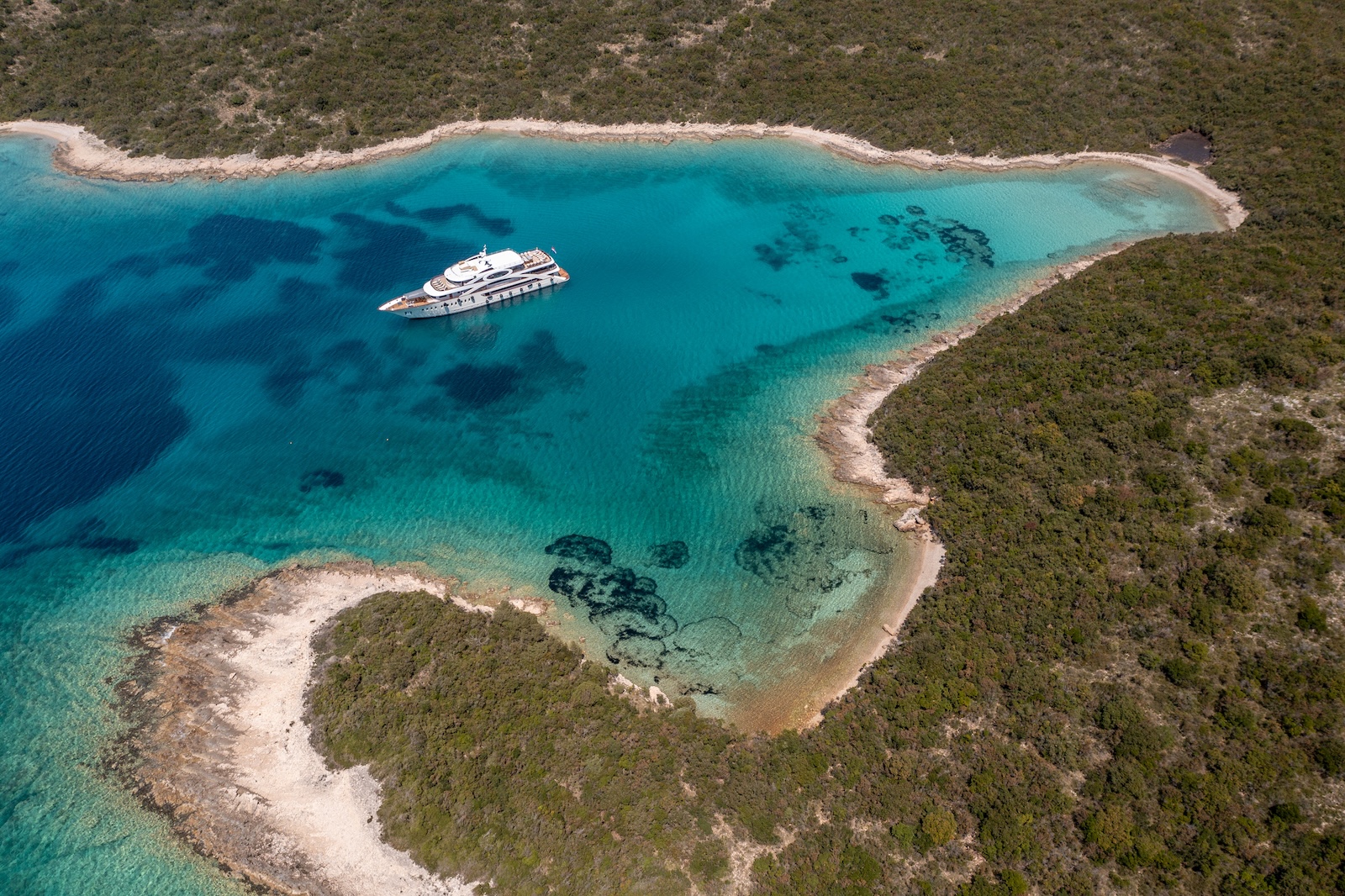 yacht anchored in secluded turquoise bay surrounded by natural coastline
