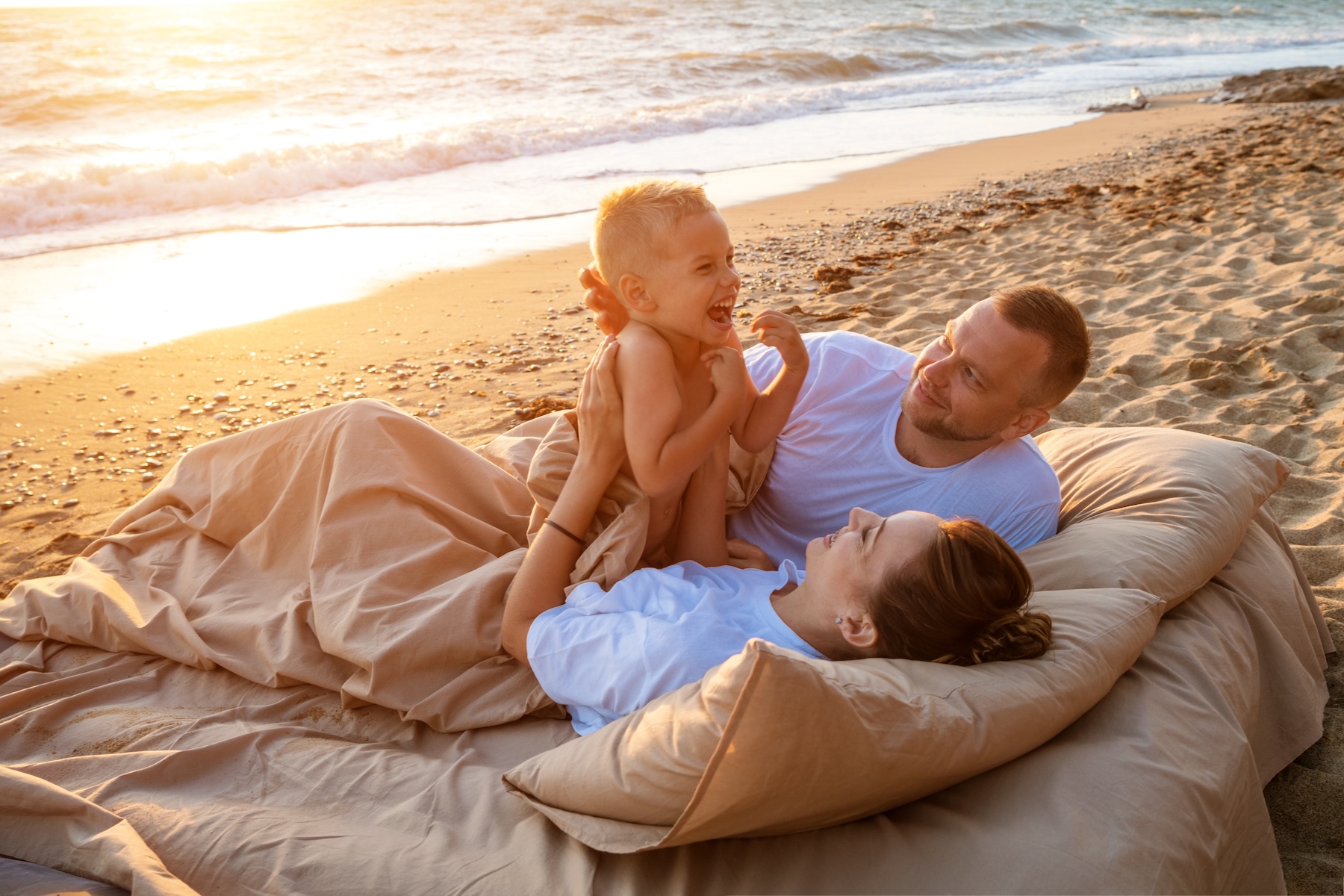 Family relaxing together on the beach during a coastal vacation at sunset