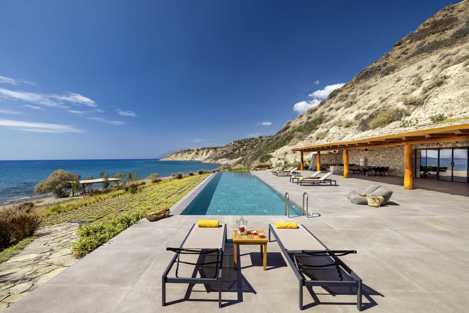 Infinity pool terrace with open-air living space overlooking the Mediterranean coastline