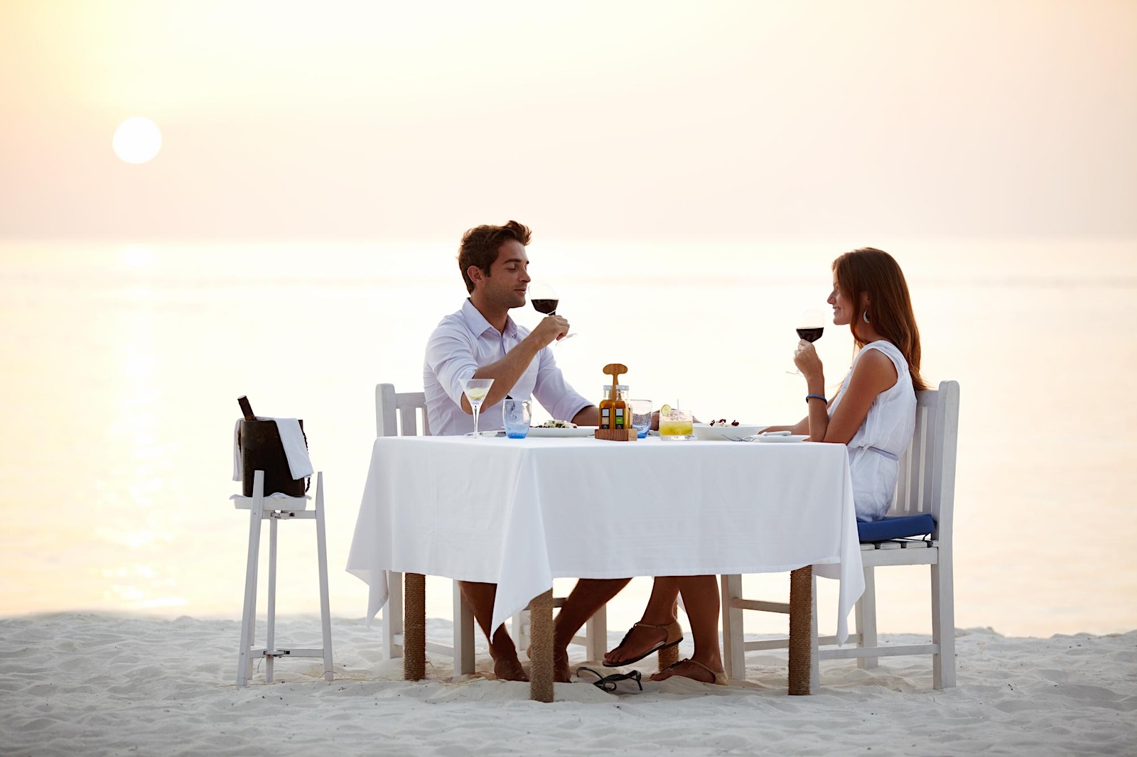 Couple enjoying a private seaside dinner during a coastal celebration at sunset