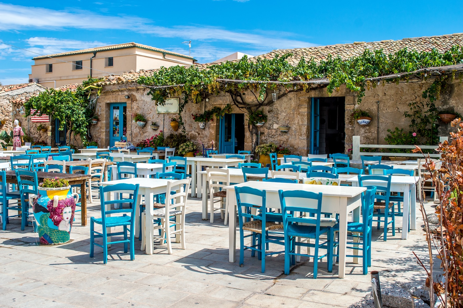 Traditional outdoor taverna with blue chairs and stone architecture in Crete