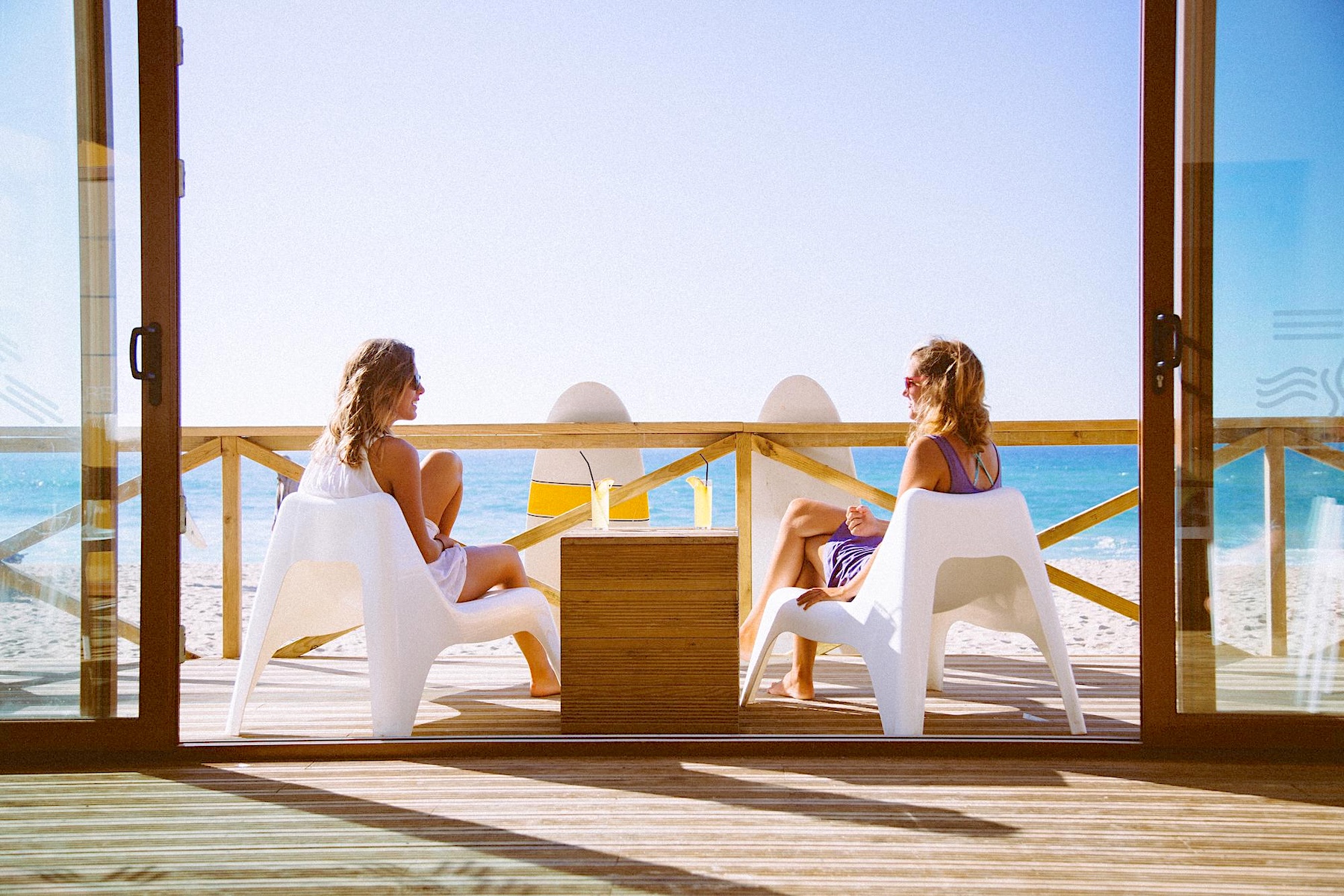 Two women enjoying conversation on a coastal terrace overlooking the sea