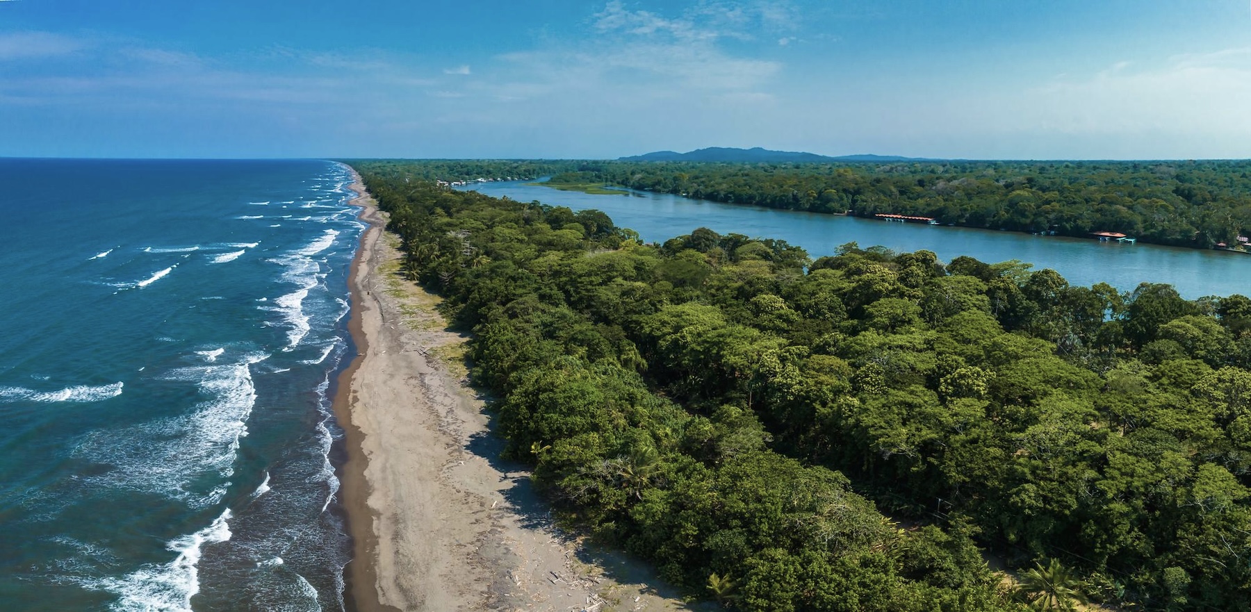 Aerial view of Costa Rica's Caribbean coastline with tropical rainforest, river, and sandy beach.