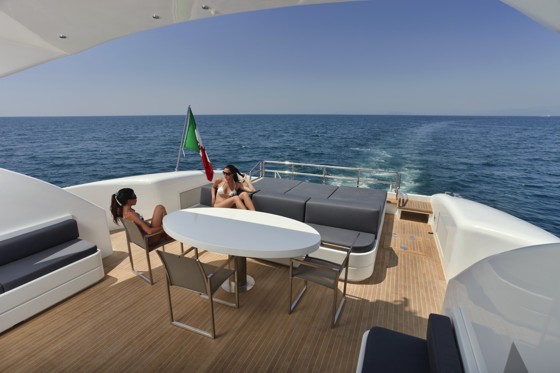 Guests relaxing on the aft deck of a private yacht while cruising along the coast during a private yacht charter.