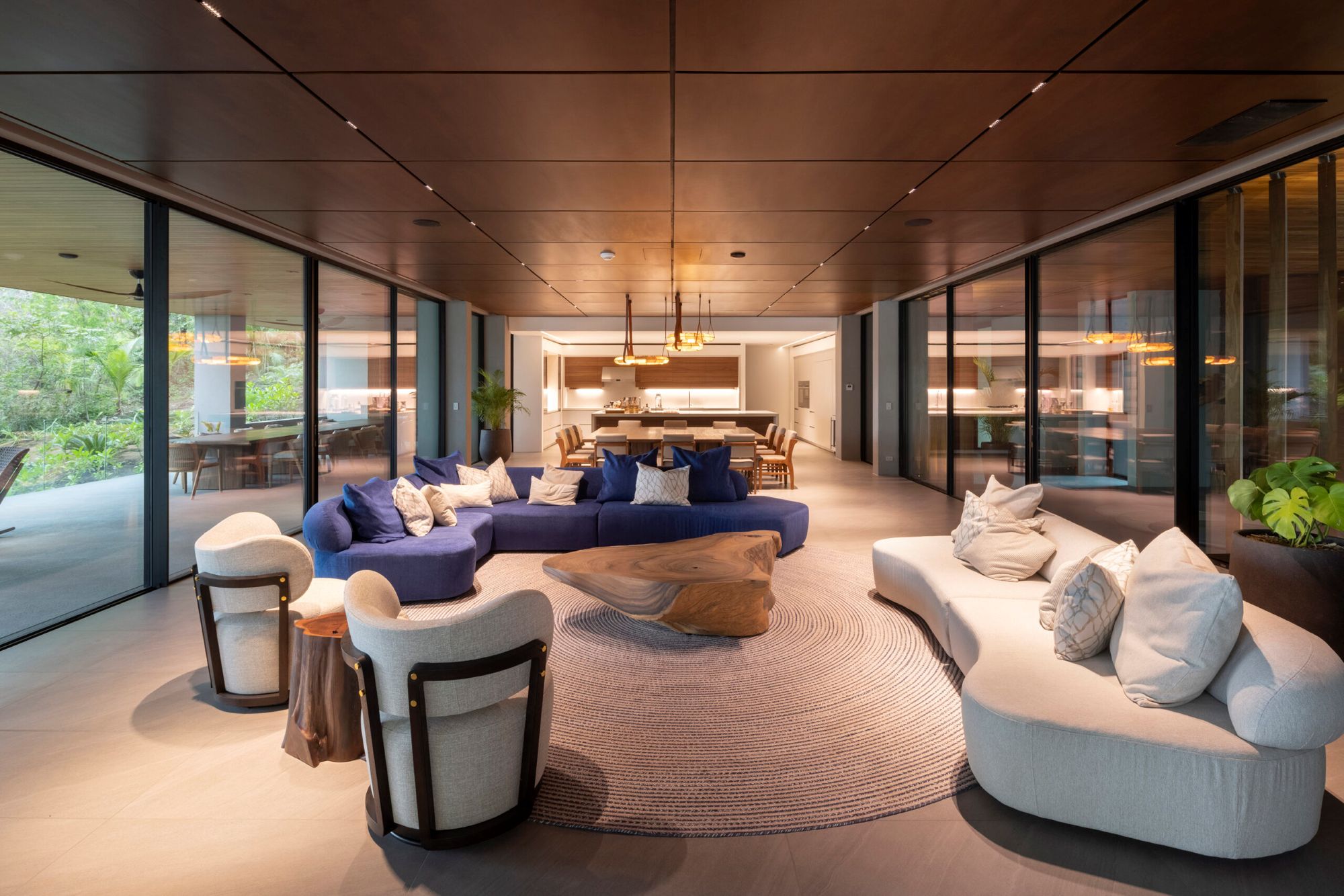 Open-plan coastal living room with curved seating and natural wood at Villa Avellana