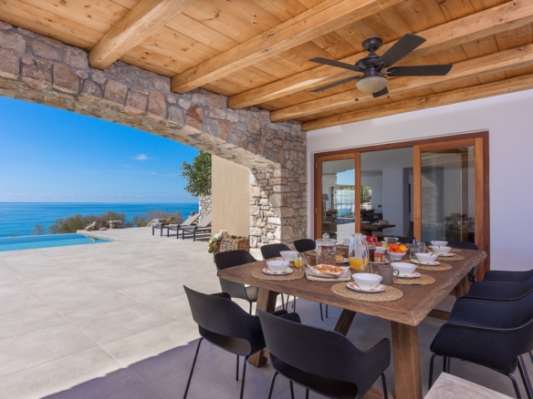 Mediterranean indoor-outdoor living space with stone arches, timber ceiling and sea view in Crete