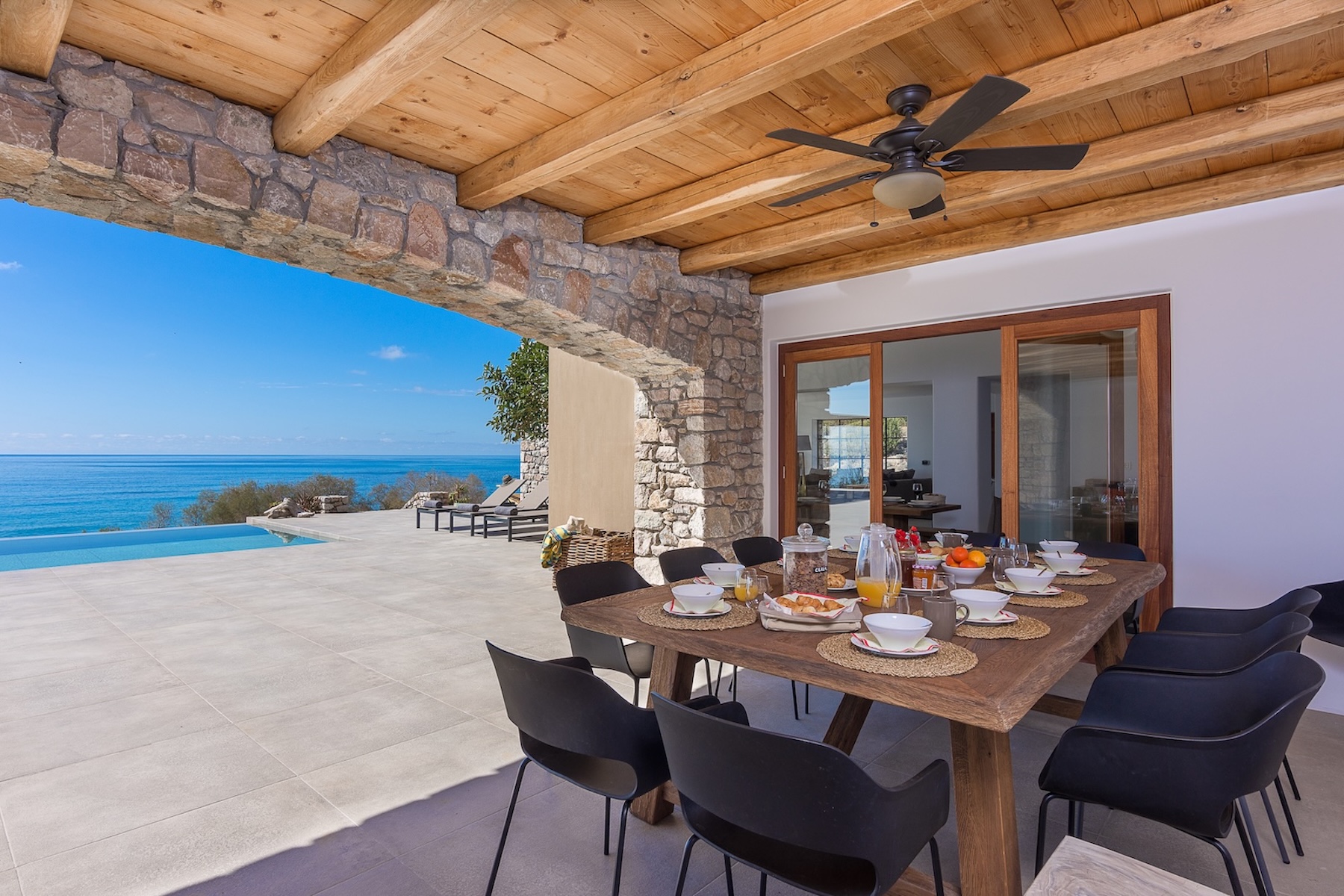 Mediterranean indoor-outdoor living space with stone arches, timber ceiling and sea view in Crete