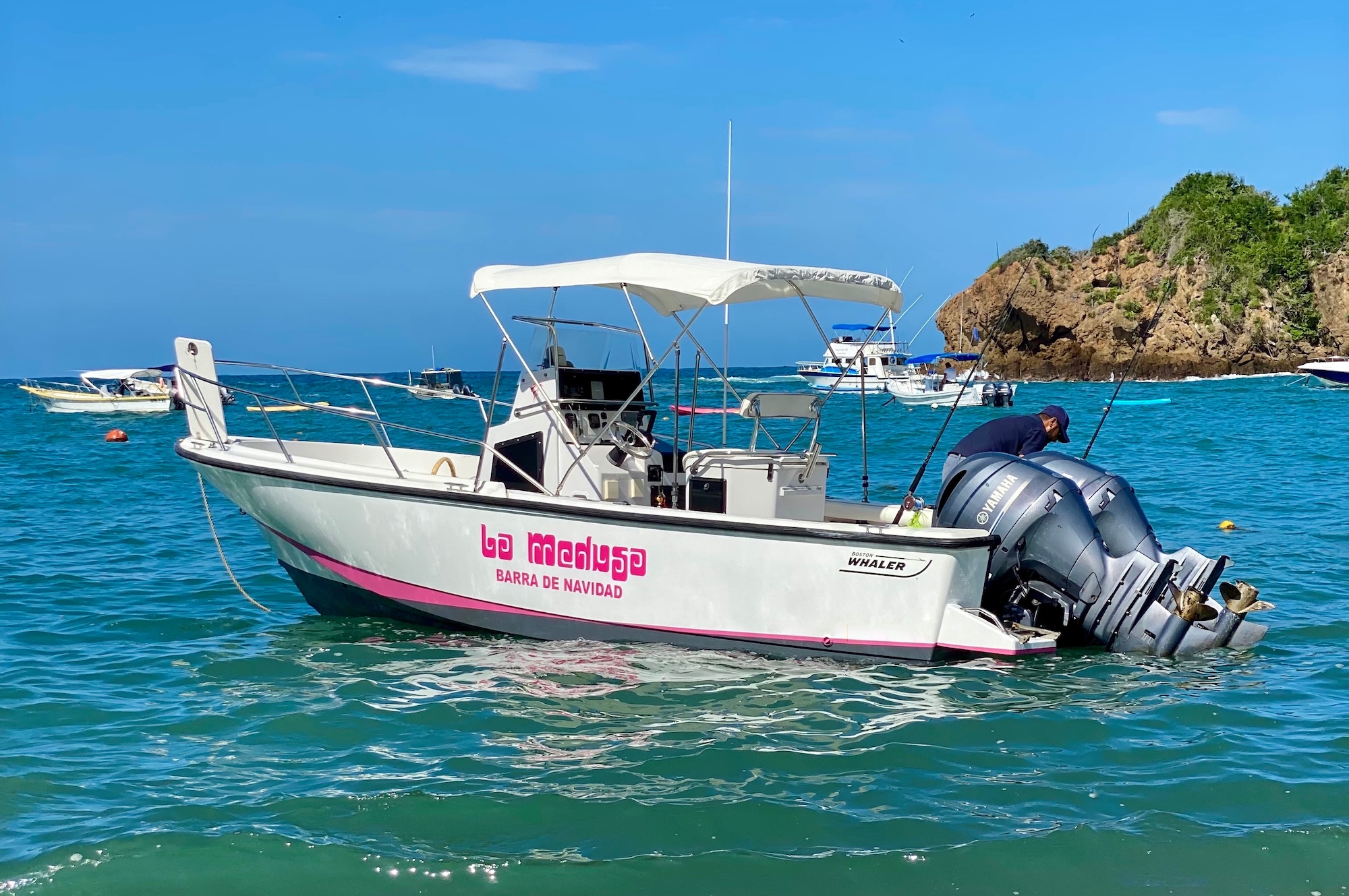 Boston Whaler on the turquoise Pacific waters off Careyes, Mexico, with the rocky coastline in the background.