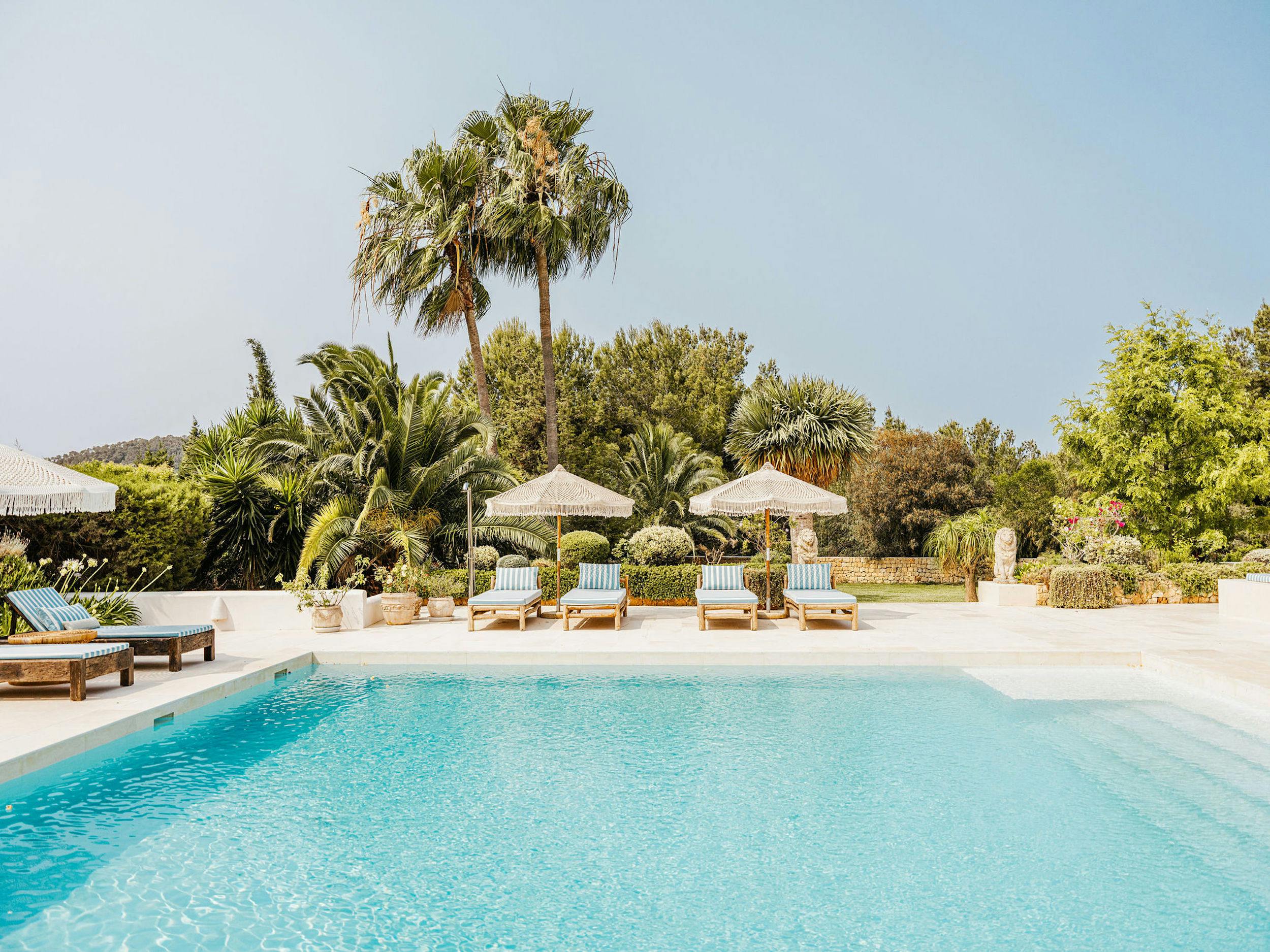 Private swimming pool at El Zafiro villa in Ibiza, with sun loungers, parasols, and Mediterranean gardens.