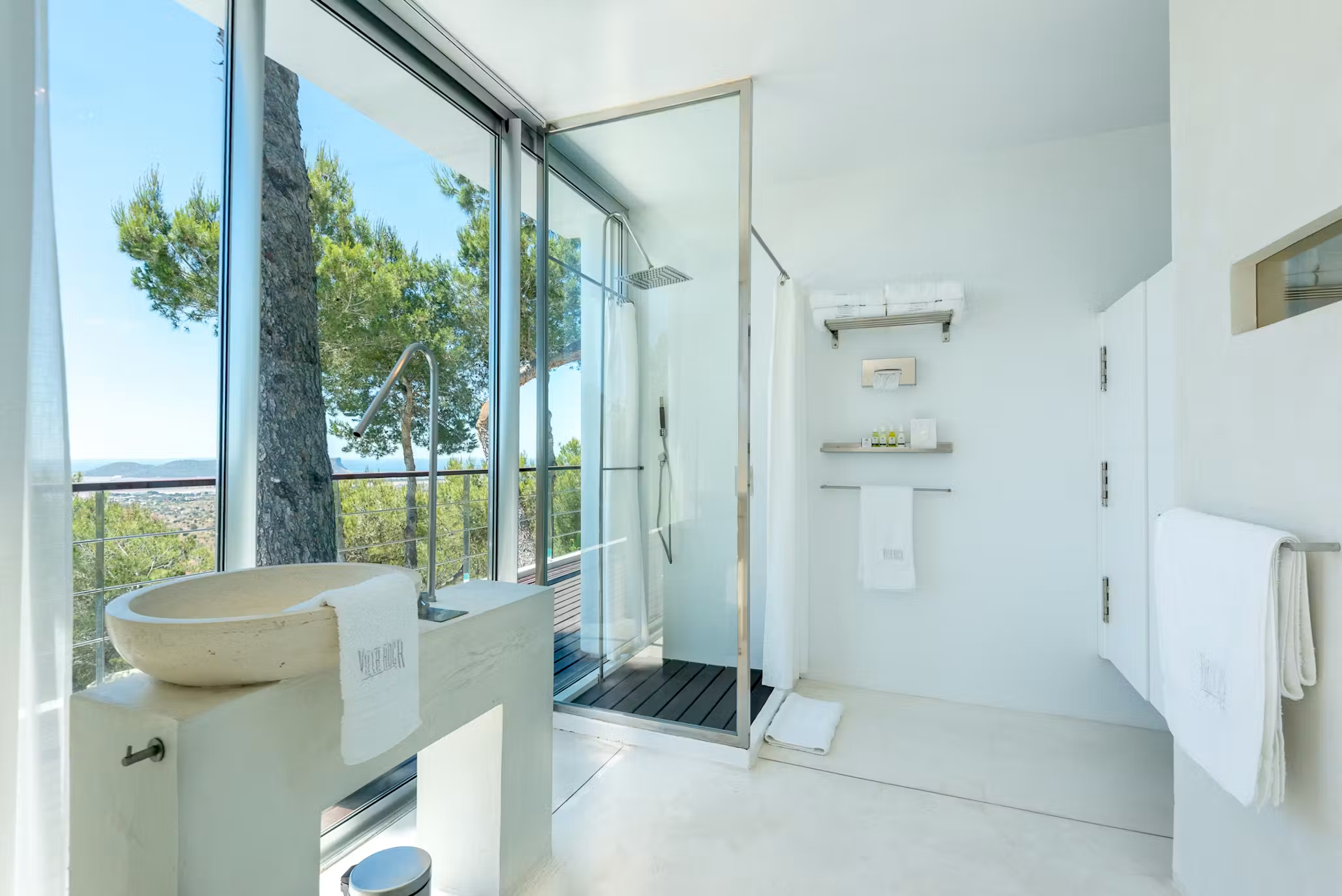 Bright bathroom at Villa Destiny Ibiza with a walk-in shower, stone basin and large window overlooking the trees