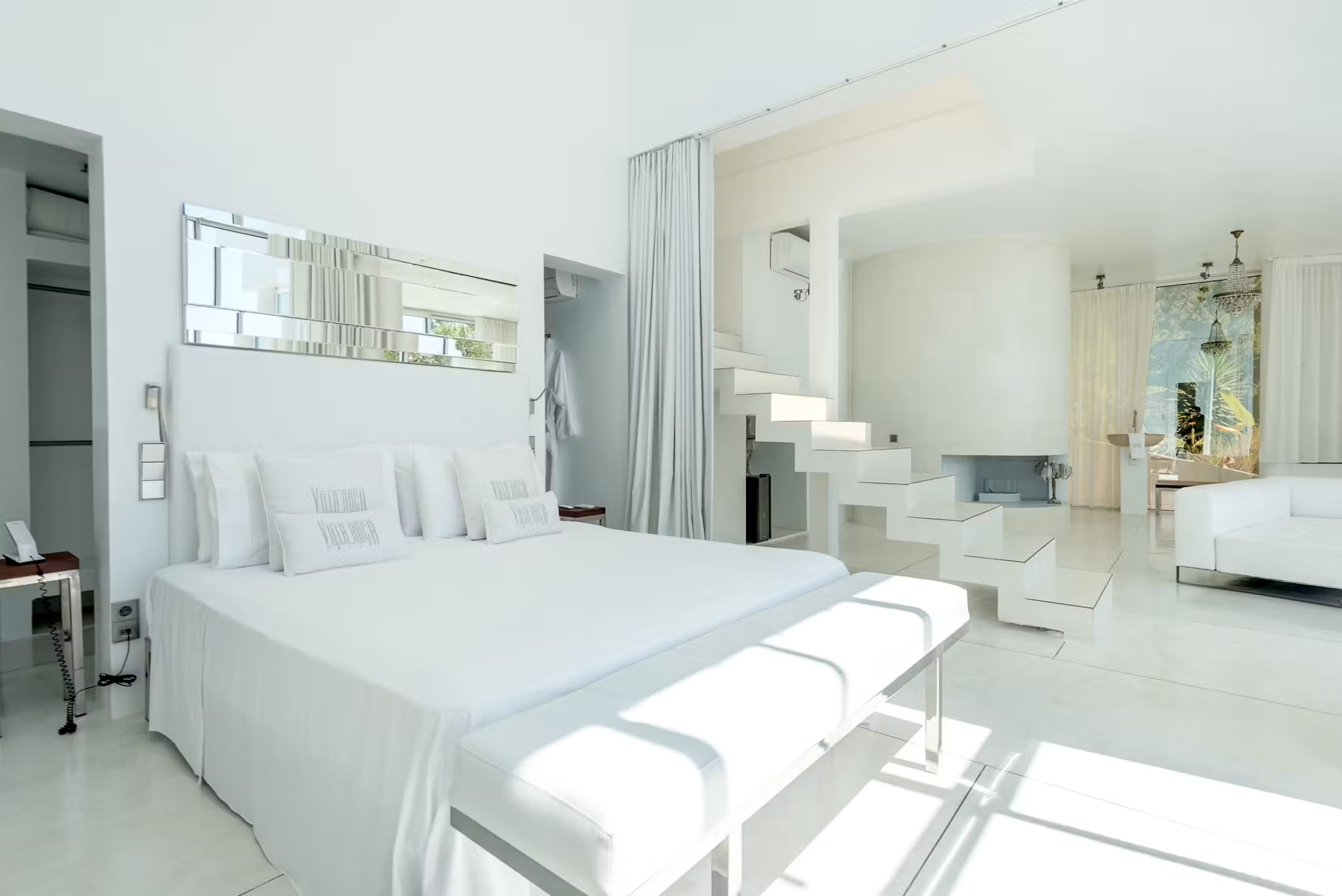 Bright bedroom suite at Villa Destiny Ibiza with a white bed, adjoining sitting area and contemporary interior