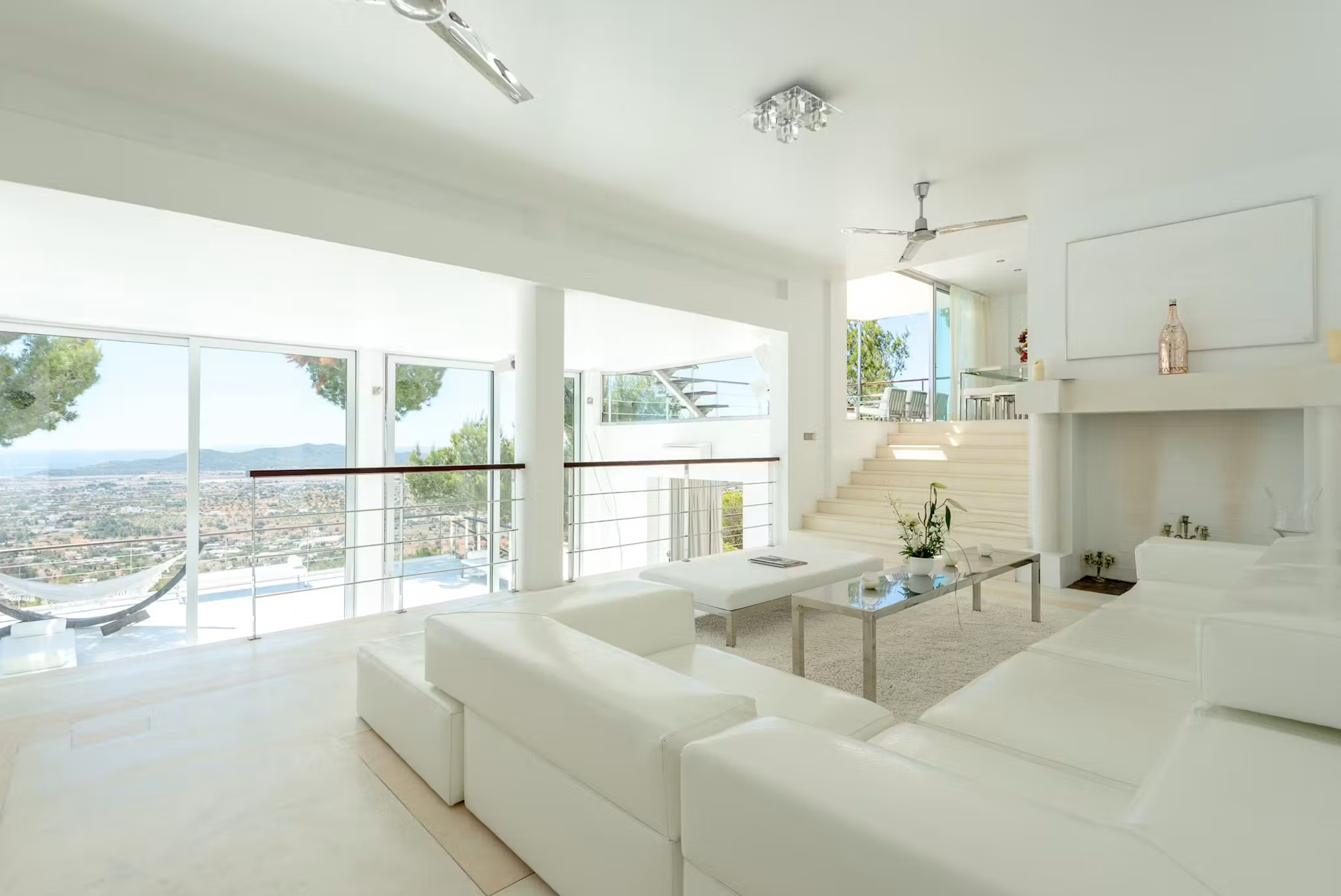 Bright white living room at Villa Destiny Ibiza, with spacious sofas, floor-to-ceiling windows and views across the surrounding landscape.