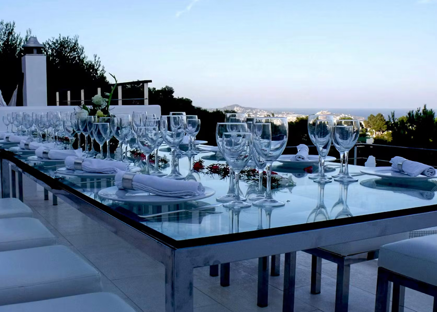 Outdoor dining table set with white napkins and glassware at Villa Destiny in Ibiza, with distant sea views