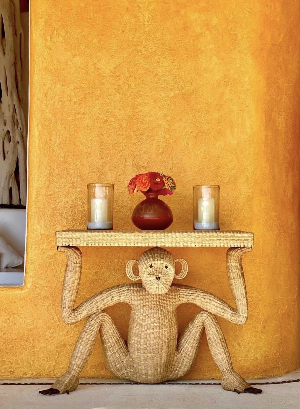 Woven monkey-shaped console table against a textured ochre wall