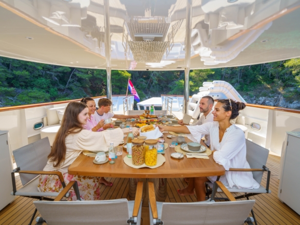 Family yacht charter with guests sharing breakfast on deck