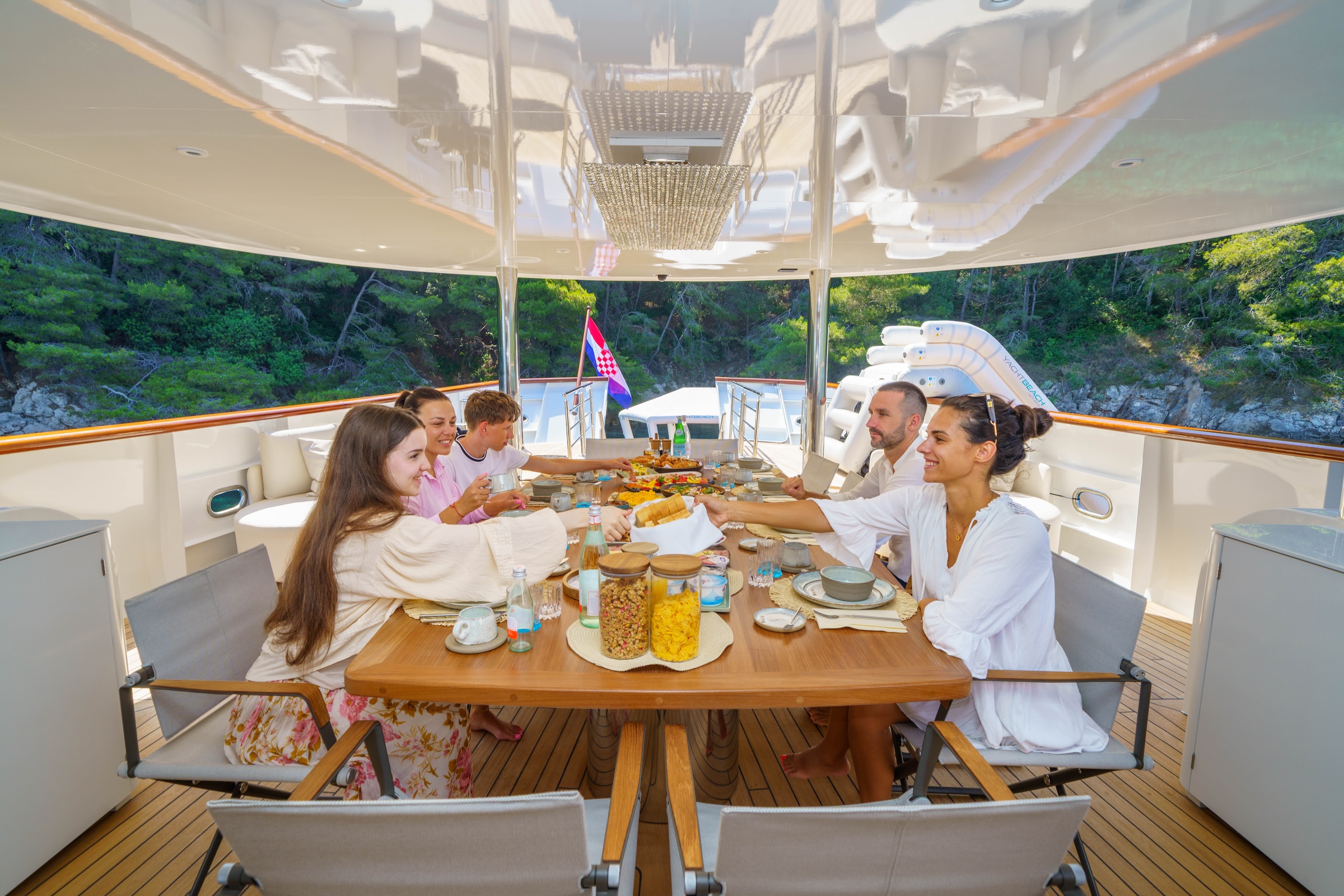 Family yacht charter with guests sharing breakfast on deck