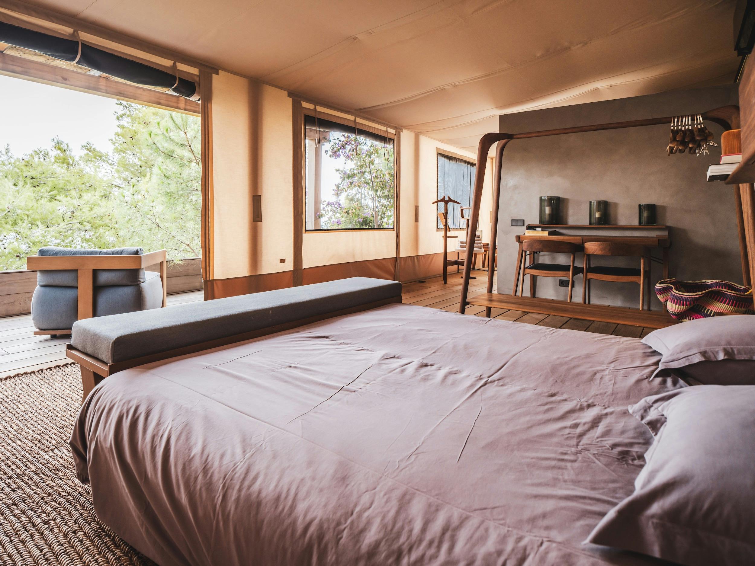 Bedroom with pale bedding, wood flooring, broad windows overlooking greenery, and a desk at Ocean Paradise in Ibiza