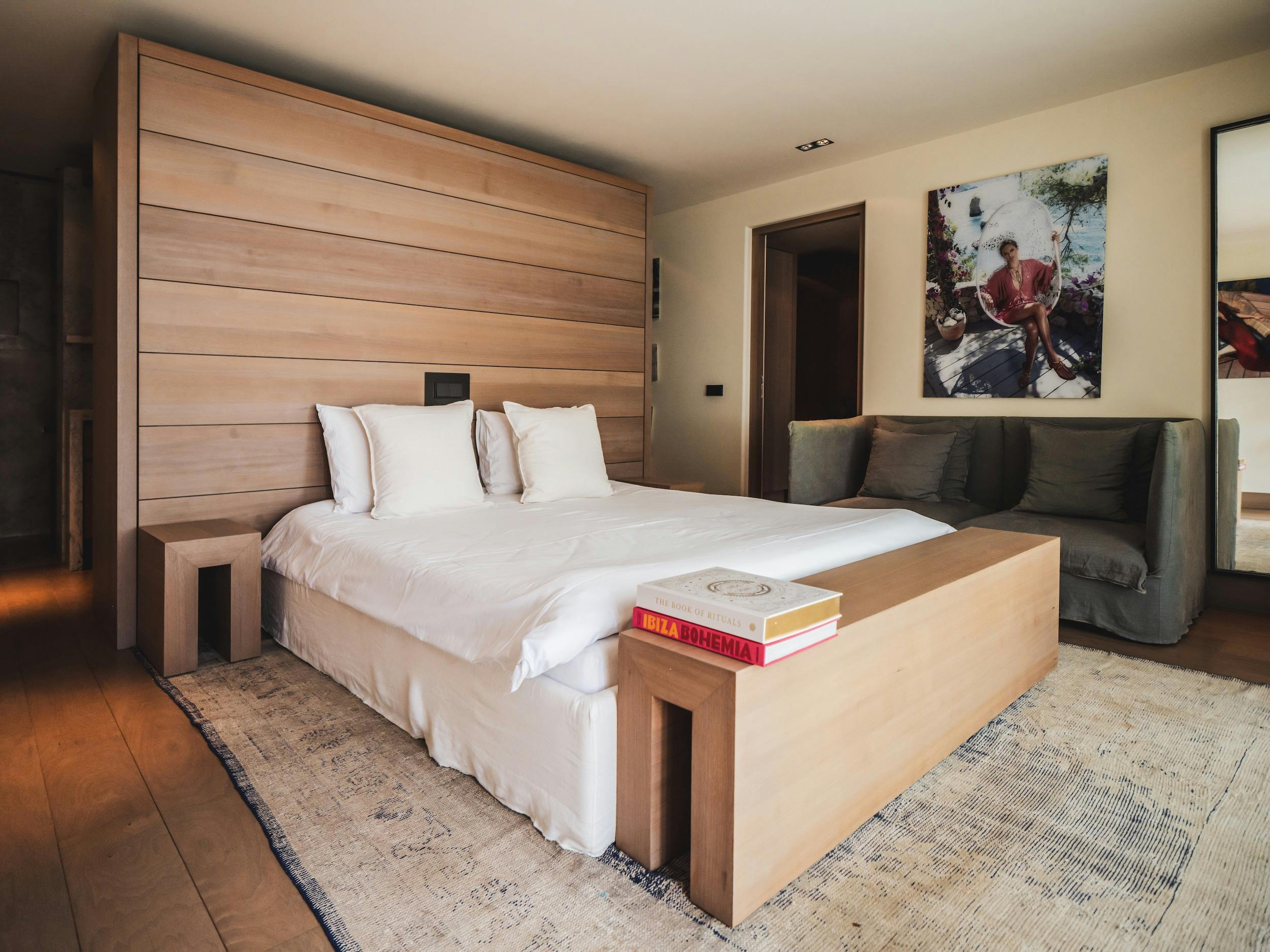 Bedroom with white bedding, a broad wood headboard, and a gray sofa at Ocean Paradise in Ibiza