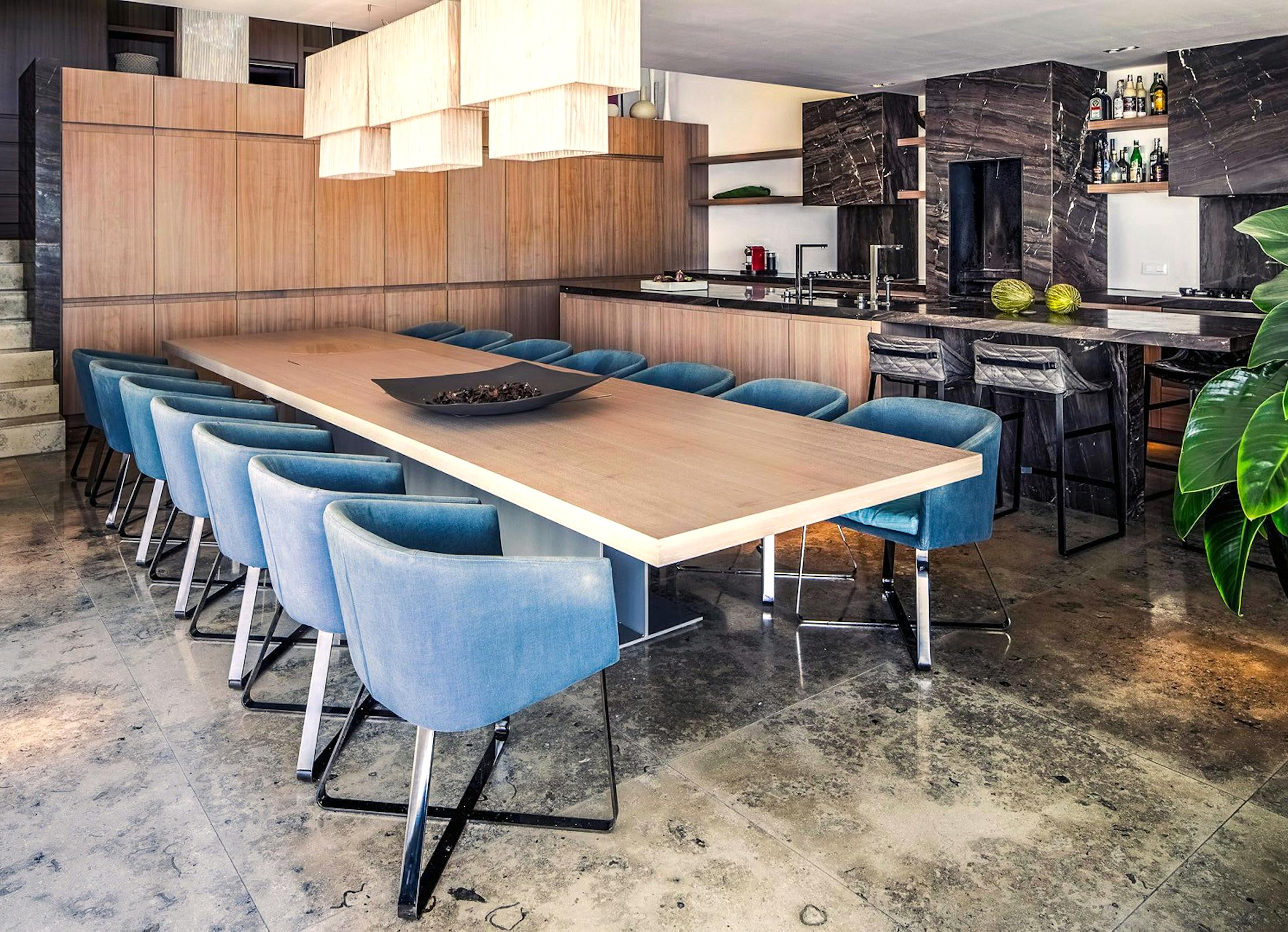 Indoor dining table with blue upholstered chairs beside the kitchen and breakfast bar at Ocean Paradise villa in Ibiza