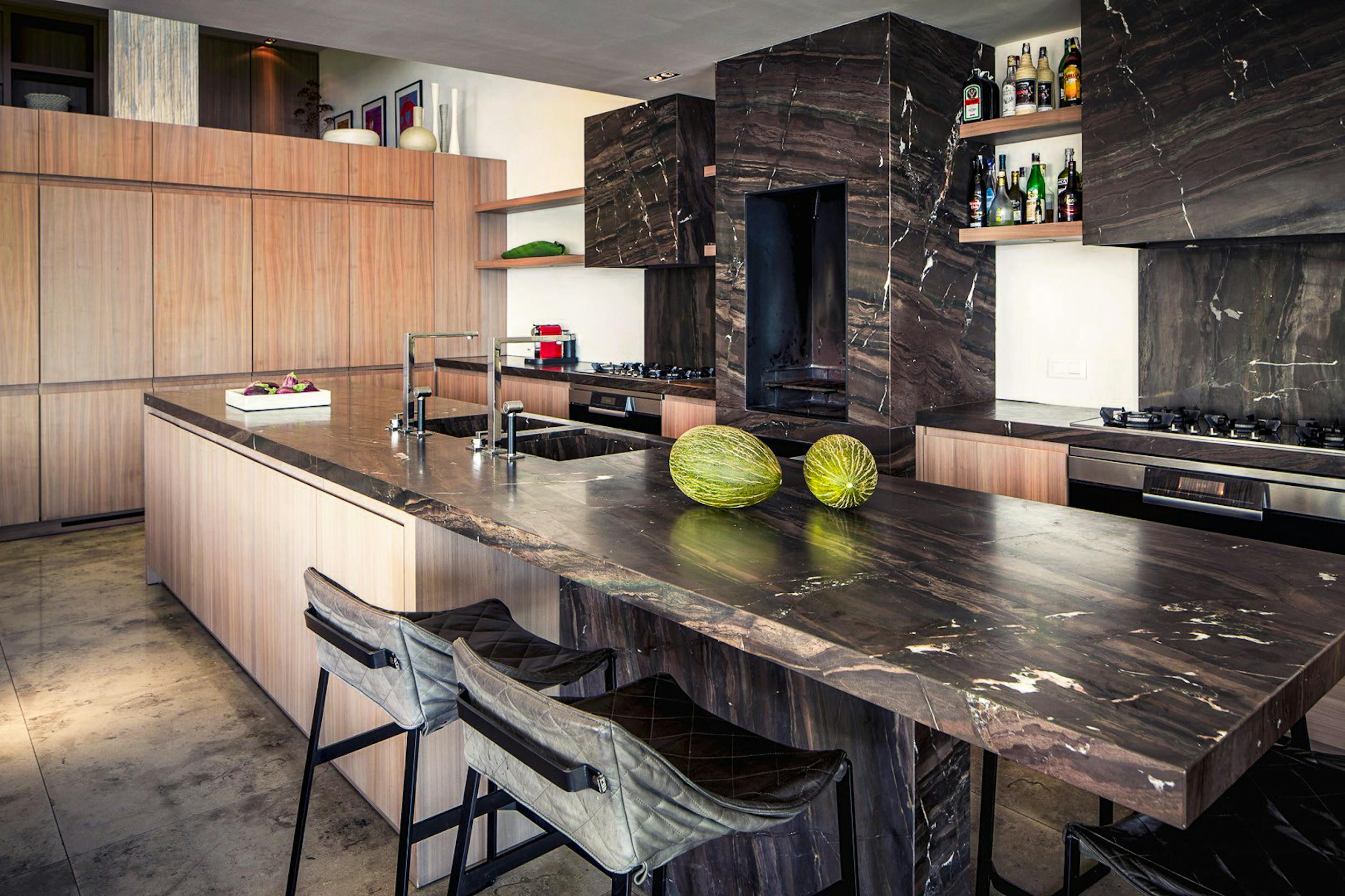 Kitchen with wood cabinetry, a dark stone island, twin sinks, and breakfast-bar seating at Ocean Paradise in Ibiza