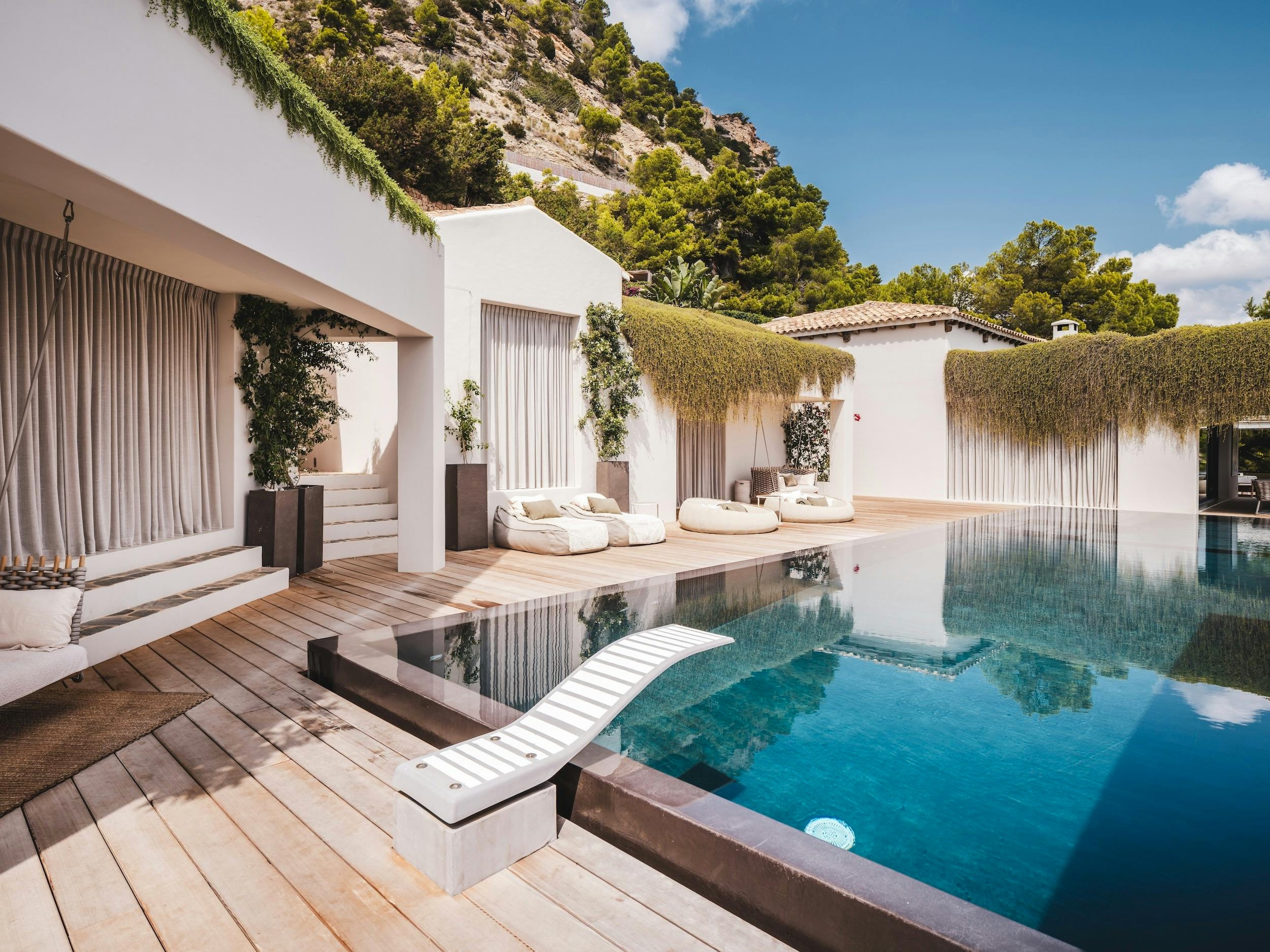 Private pool beside the white villa and wooden deck with sun loungers at Ocean Paradise in Ibiza