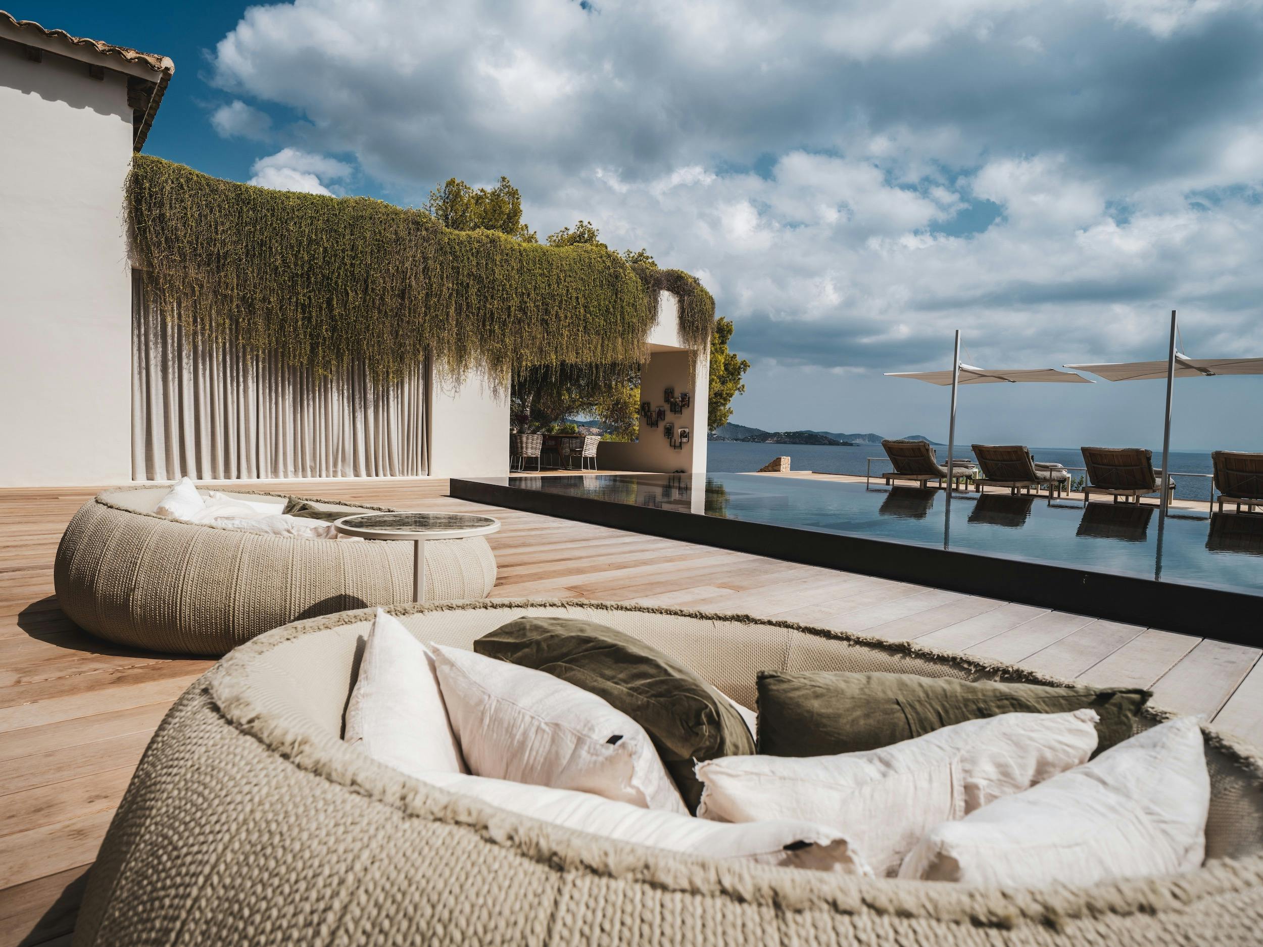Rounded woven seating on a wooden terrace beside the pool, with Mediterranean views at Ocean Paradise in Ibiza