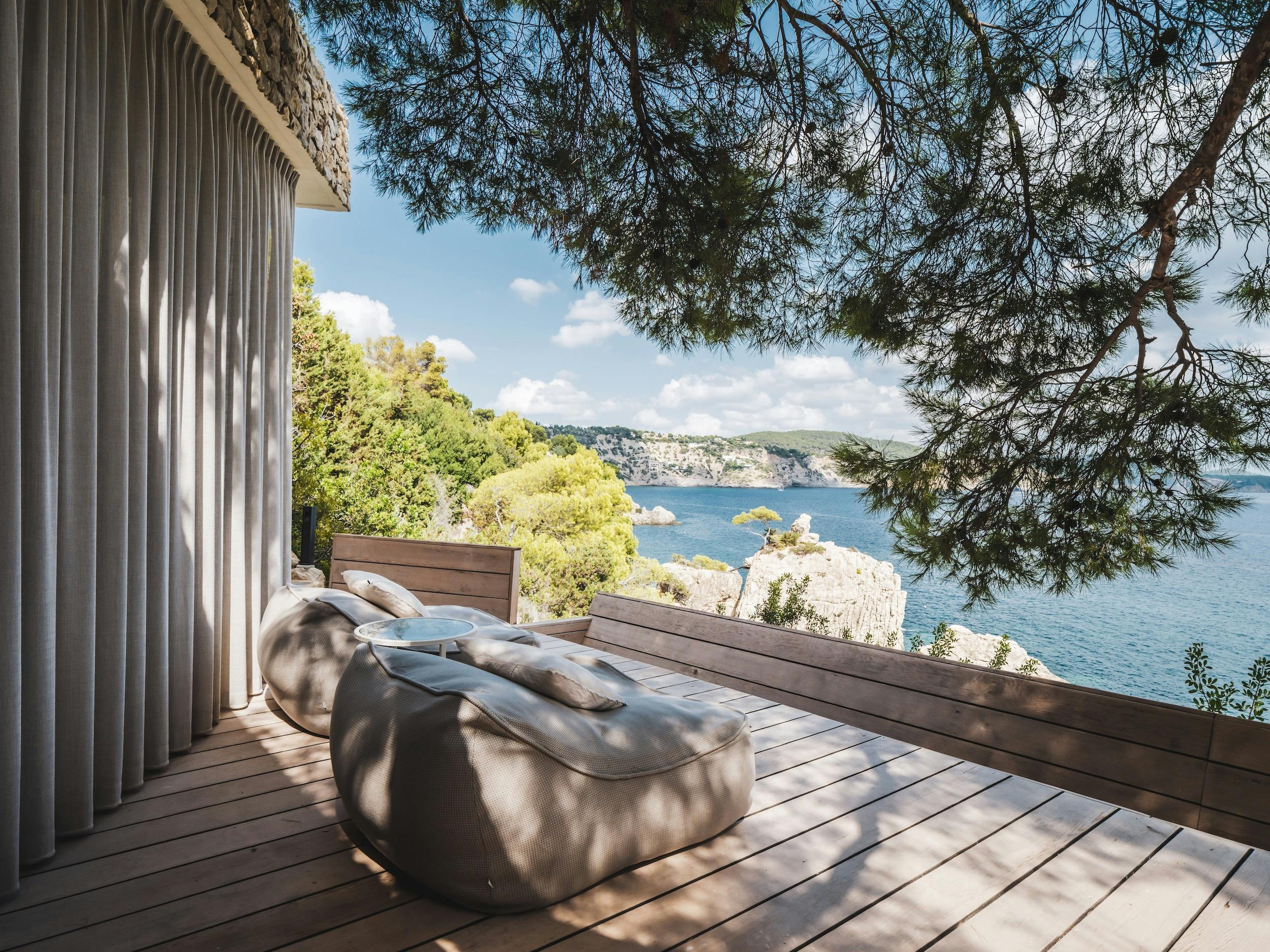 Cushioned loungers on a shaded wooden terrace overlooking the Mediterranean at Ocean Paradise villa in Ibiza