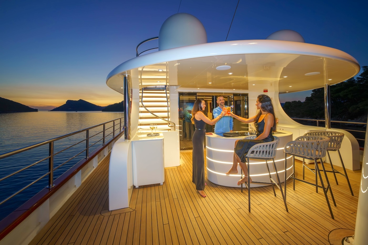 Guests enjoying drinks on the deck of a private yacht at sunset
