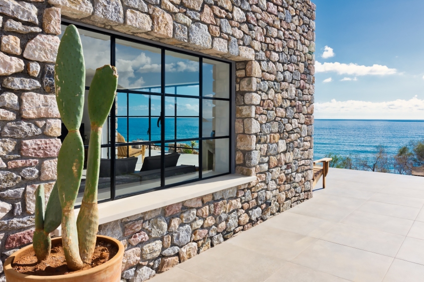 Natural stone wall with black-framed window and cactus overlooking the Libyan Sea in Crete